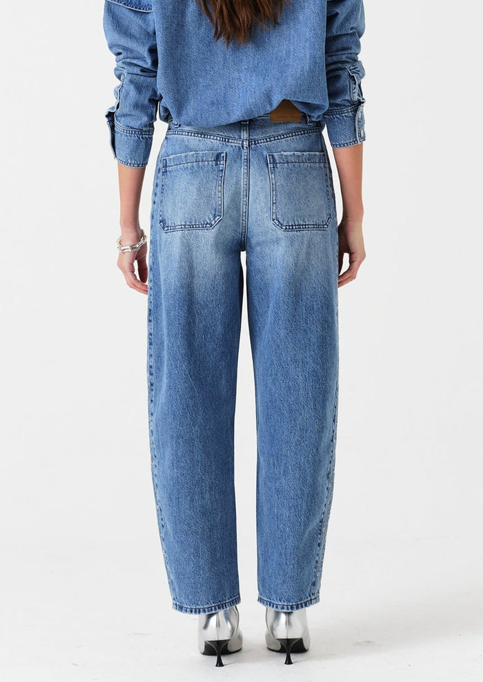 Person wearing blue jeans and a matching denim shirt on a white background