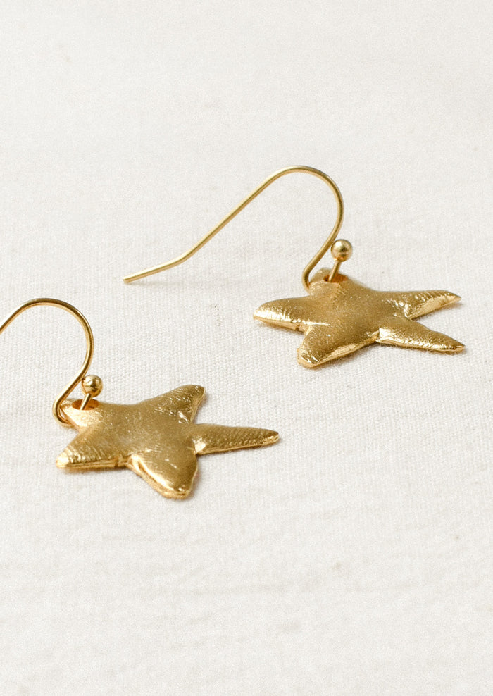 A pair of gold earrings with large dangling star shaped charms.