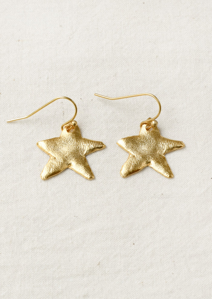 A pair of gold earrings with large dangling star shaped charms.