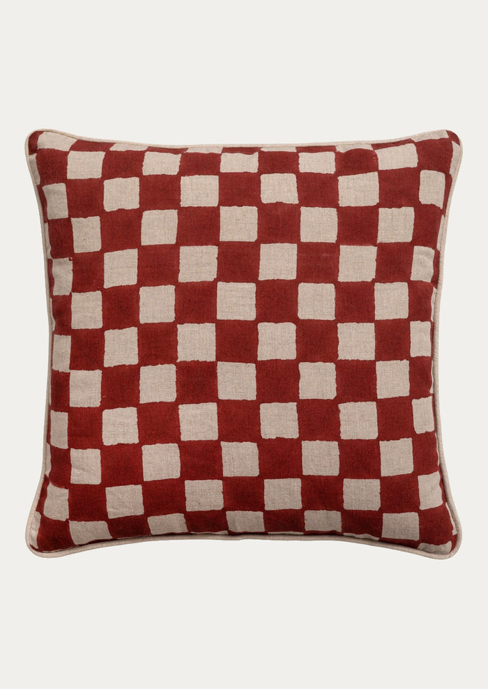A square throw pillow featuring a red and beige checkered pattern, shown against a plain light gray background.