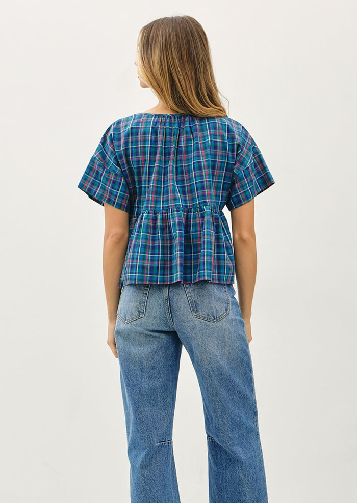 Person wearing a blue plaid shirt and jeans on a white background