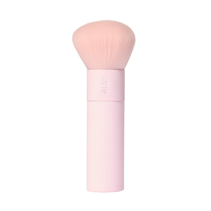A tarte cosmetics pink makeup brush with soft, rounded bristles and a pink handle, on a white background.