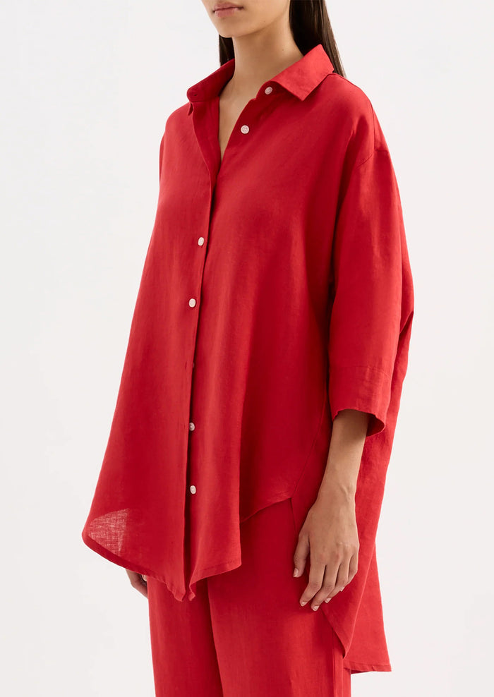A woman wearing a relaxed red linen shirt.
