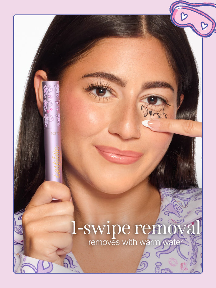 A woman removing tartelette tubing mascara with limited edition roller rabbit collab cap, with text reading '1-swipe removal' and 'removes with warm water.'