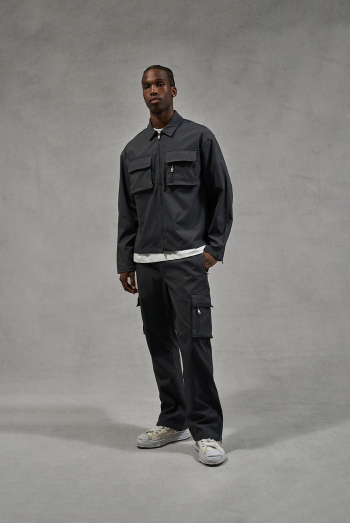 A man wearing a long sleeve grey shirt and matching pants against a plain background.